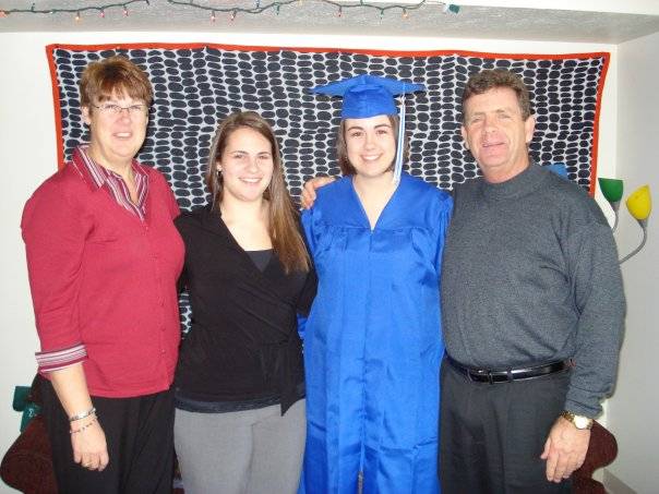 Megan wearing cap and gown smiles with family before graduation in 2008